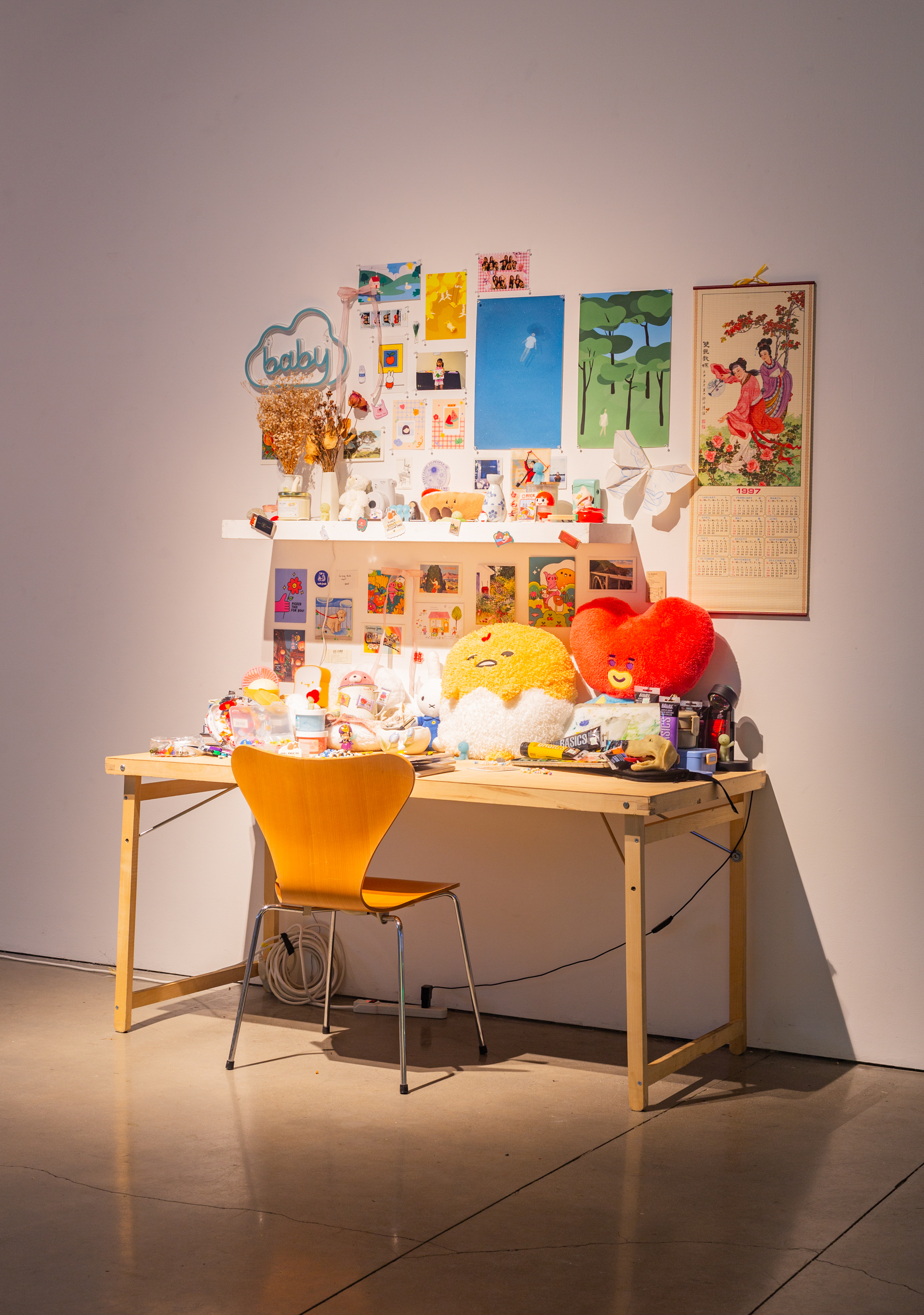 A wooden desk overly decorared with various plushies, collectibles, and printed photos.